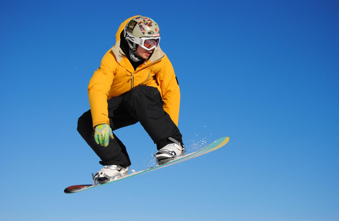 man in yellow jacket riding snowboard